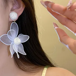 Close-up of elegant white mesh flower earrings worn on ear showing delicate petal texture