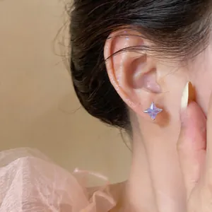 Primo piano di un elegante orecchino a stella in zircone viola indossato sull'orecchio