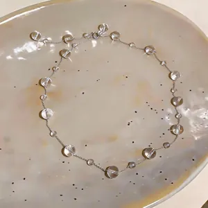 Dettaglio di una collana minimalista con perle di vetro trasparenti irregolari