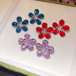 Close-up of sparkling crystal flower stud earrings in blue, red, and purple colors