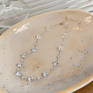 Dettaglio di una collana con perle di vetro trasparente di varie dimensioni su catena d'argento