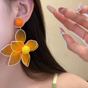 Macro detail of a vibrant orange mesh flower earring with a yellow textured core