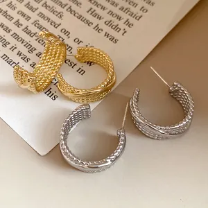 Detailed macro view of textured C-shaped gold and silver earrings with vintage style