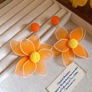 Macro detail of sweet orange mesh flower earrings with woven centers in a jewelry box