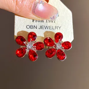 Macro detail of elegant red crystal flower stud earrings on a vintage jewelry card