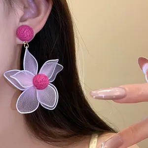Detailed macro view of pink mesh flower drop earrings worn by an elegant female model