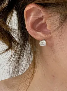 Detailed view of a unique irregular sparkling zirconia stud earring worn on a model's ear