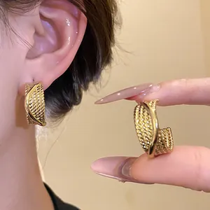 Detailed close-up showing the mesh texture of gold C-shaped hoop earrings on model.