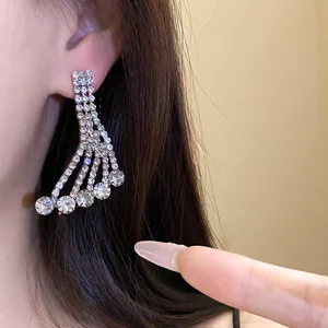 Close-up of elegant sparkling rhinestone dangle earrings worn on ear with silver finish.