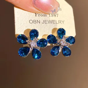 Close-up detail of blue crystal flower earrings with sparkling silver studs