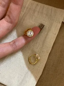 Close-up detail of gold-plated hoop earrings featuring a large brilliant zircon stone