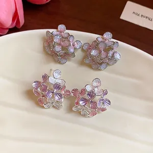 Elegant floral stud earrings with shimmering oil-dripping petals on a ceramic tray