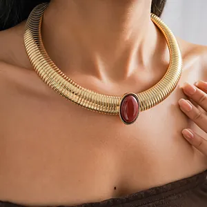 Close-up detail of a vintage gold chunky necklace with a bold red oval resin stone