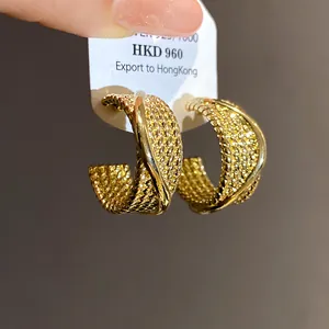 Close-up of gold-plated textured C-shaped hoop earrings with a sophisticated retro design