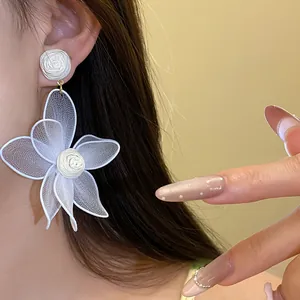 Detailed close-up of elegant white mesh flower earrings with delicate rose bud center
