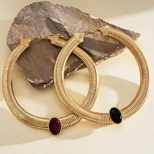 Close-up of retro chunky gold necklaces with oval resin stones in red and black.