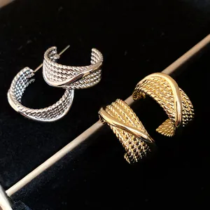 Macro view of textured C-shaped stud earrings in elegant gold and silver finishes