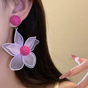 Close-up detail of pink mesh flower earring with woven texture worn by a model