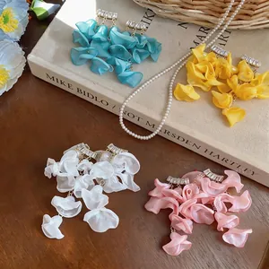 Elegant summer resort chiffon petal earrings with sparkling zircons on wooden background.