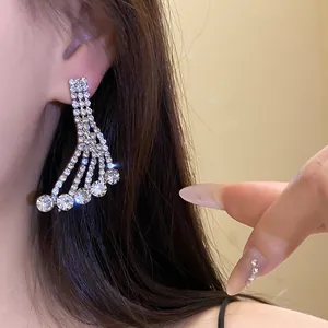 Detailed macro shot of elegant silver-tone rhinestone tassel dangling earrings on ear