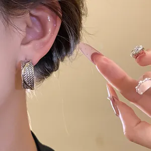 Elegant close-up view of textured silver C-shaped hoop earrings worn on a model ear