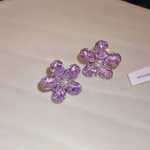 Detailed macro shot of elegant purple rhinestone flower stud earrings with silver needles