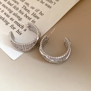 Detailed view of textured silver C-shaped hoop earrings with a vintage finish