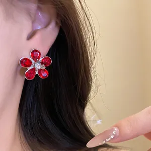Detailed close-up showing an elegant red crystal flower stud earring on a model's ear