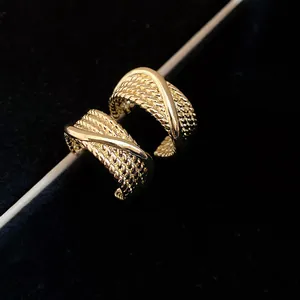 Macro detail of vintage gold C-shaped earrings with intricate woven texture design