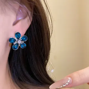 Close-up detail of blue crystal flower stud earring with elegant silver pin finish