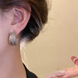 Close-up of textured silver-tone C-shaped hoop earrings worn by a model for detail view.