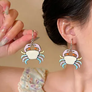 Close-up of cute colorful cartoon crab enamel earrings on a model's ear