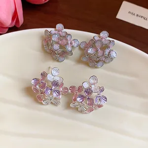 Close-up detail of elegant enamel flower stud earrings with glitter and purple petals on a plate