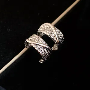 Macro detail of textured C-shaped silver earrings with vintage braided design
