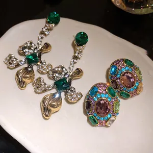Macro detail of vintage-style floral and colorful oval crystal earrings set on a plate