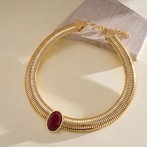 Macro view of vintage gold ribbed choker necklace with large oval burgundy resin gem