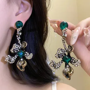 Detail of vintage floral drop earrings with emerald green stones and sparkling crystals.