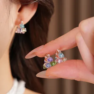 Close-up of geometric square hoop earrings featuring colorful glass block crystals.