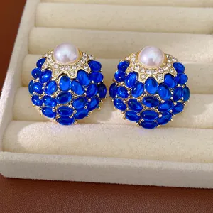 Gros plan de boucles d'oreilles vintage bleues avec perle centrale et halo de strass