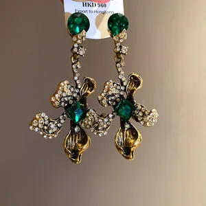 Close-up of vintage flower drop earrings with green rhinestones and antique gold finish