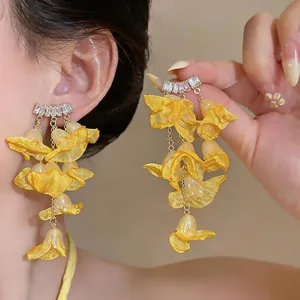 Close-up view of yellow chiffon flower tassel earrings with sparkling zircon studs on a model