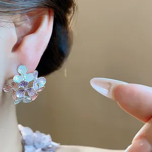 Close-up detail of elegant multi-colored oil drip flower stud earrings on a model's ear.