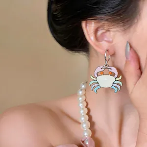 Detailed view of cute cartoon crab enamel drop oil hoop earring worn on model ear