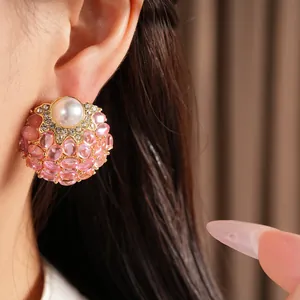 Vue détaillée de boucles d'oreilles vintage avec perle et cristaux roses sur l'oreille.