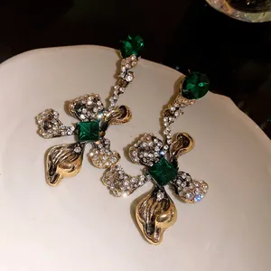 Detailed shot of vintage gold flower earrings with emerald green crystals and sparkling rhinestones