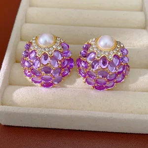 Détail macro de boucles d'oreilles vintage avec perles et pierres violettes dans un écrin
