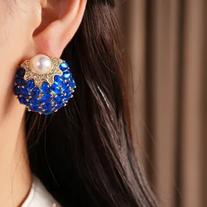 Gros plan de boucles d'oreilles vintage avec une grande perle et des pierres cabochons bleues