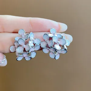 Macro detail of elegant silver flower stud earrings featuring shimmering glitter oil effect