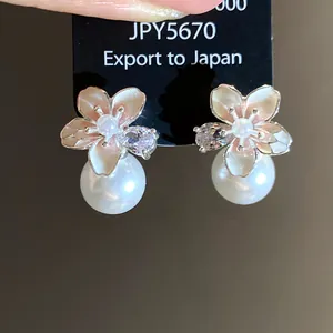 Primo piano di orecchini a lobo a fiore con perle e dettagli in zircone marquise.