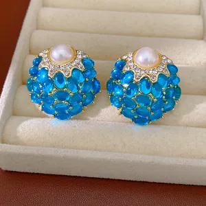 Gros plan sur des boucles d'oreilles vintage dorées avec pierres bleues et perle